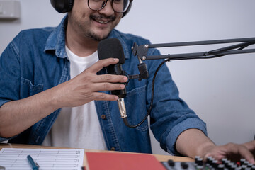 Close-up of young man recording a podcast with microphone and headphones, modern content creation and broadcasting concept.