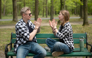 Father And Little Daughter Playing Clapping Game In Family Look While Sitting On A Bench