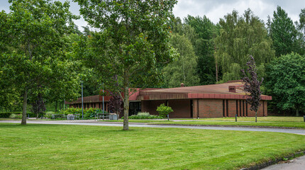 Red roofed brick building in green cemetery.