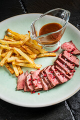Deliciously sliced beef steak rests beside golden crispy fries, all elegantly presented with sauce