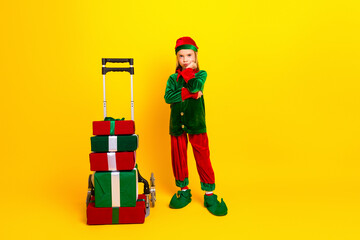 Cute little elf character posing with festive gifts and trolley on yellow background, showcasing holiday cheer and fun