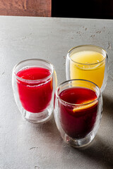 Three vibrant drinks in deep red, bright yellow, and citrus capture attention elegantly