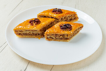 Three aromatic baklava slices topped with nuts, inviting sweetness on a bright surface