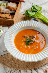 Warm bowl of rich soup with tender meat, served with crusty bread and fresh herbs on a rustic table