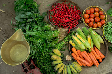 A vibrant assortment of various fresh vegetables and aromatic herbs beautifully displayed in a lively market setting