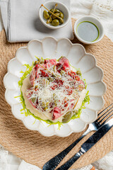 Vibrant salad with fresh ingredients, cheese, and olives, artfully arranged on a textured plate