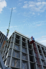 Construction crane and freight elevator at the construction site of a house under construction. View from below.
