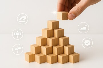 Hand placing a wooden cube on top of a pyramid of other wooden blocks, symbolizing growth, success, and achievement, with business-related icons surrounding the pyramid.