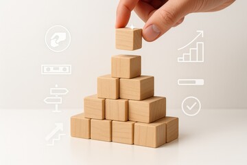 Building a pyramid with wooden blocks symbolizes growth, success, and the completion of a goal, with a hand placing the final piece, illustrating concepts of development and achieving ambitions.
