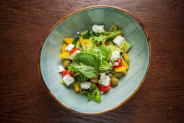 A bright salad featuring multicolored vegetables, greens, and crumbled feta cheese served in a bowl