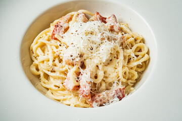 Indulgent spaghetti coated in creamy sauce, enhanced by crispy bacon and cheese, awaits enjoyment