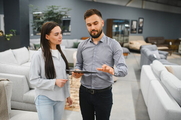 Sales consultant assisting female buyer choosing furniture