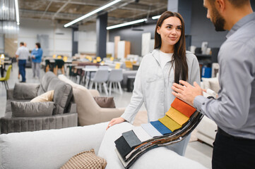 Female buyer choosing sofa fabric sample in furniture store