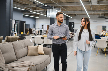 Naklejka premium Sales consultant helping woman choosing furniture in store