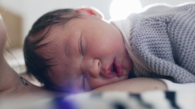 Close-up of a newborn baby’s peaceful face resting on mother’s chest, the infant’s delicate features, capturing the serene bond and pure love shared between them