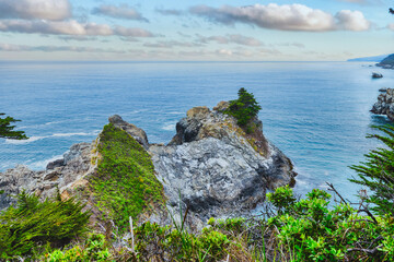 View from the campground area above McWay Falls in Big Sur, California. Scenic cliffs and turquoise waters framed by cypress trees create a unique and beautiful perspective of the Pacific coast