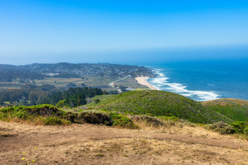 Scenic view of Highway 1 coastline from Gray Whale Cove Trail near Pacifica, California, with ocean waves, rugged cliffs, and lush green hills along the Pacific coast