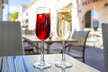 Two glasses of refreshing sangria cocktails on outdoor terrace table, red and white versions with fruit, perfect summer drinks in Mediterranean setting