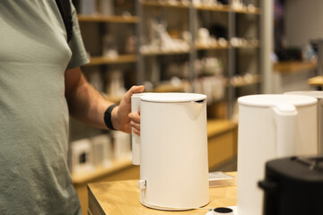 Closeup of man choosing electric kettle at electronics store.