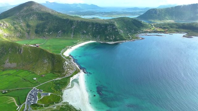 Stunning aerial view capturing the beauty of Haukland Beach in Lofoten, Norway. The breathtaking combination of turquoise water, golden sands, and vibrant green hills creates a serene landscape.