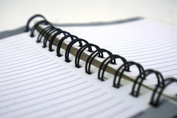 A close-up view of an open spiral notebook with white lined paper and a black coil binding, emphasizing organization, writing, and education through detail.