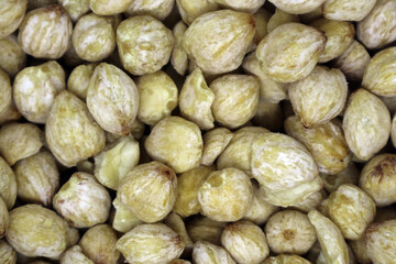 A macro close-up of a pile of shelled candlenut seeds (kemiri), showing their texture and color, a raw cooking ingredient for Southeast Asian spice pastes.
