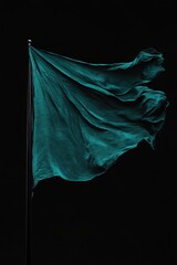 Closeup of teal satin flag fluttering in dramatic light on black