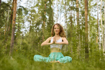 A woman practices yoga in a lush forest, enhancing her connection to nature and wellbeing