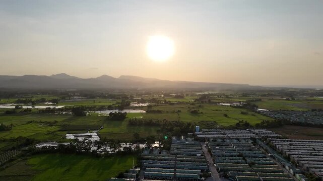 Aerial drone view of Naic Cavite countryside in the Philippines with mountains, trees, grasslands, and the sun casting a warm golden glow over the rural tropical landscape.