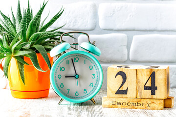 Wooden calendar with the date December 24.Monthly calendar for planning and management concept with alarm clock on wooden background
