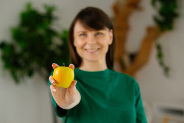 Close up of a fresh green apple held by a young attractive woman. Selective focus on fruit, healthy...