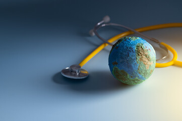 Stethoscope wrapped around globe on blue background. Save the wold, Global healthcare and Green Earth day concept.