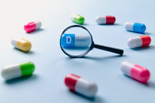 Pills,vitamin capsules through magnifying glass on white background. Vitamin D, food supplement, capsule.