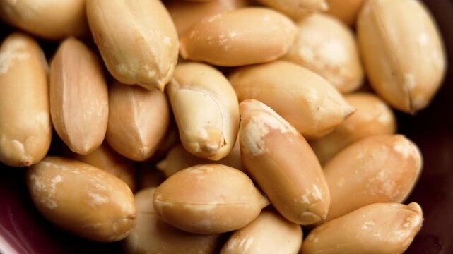 Peeled roasted peanut kernels in a wooden bowl. Macro. Rotation