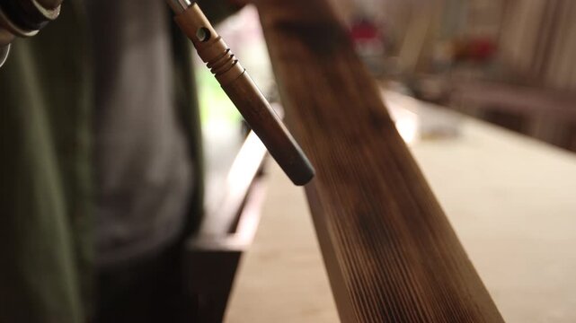 A person is painting a wooden board with a brush