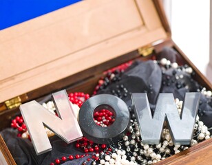 Wooden box open, revealing words "NOW" and beads