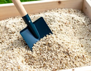 Wooden box filled with light beige sand, dark shovel