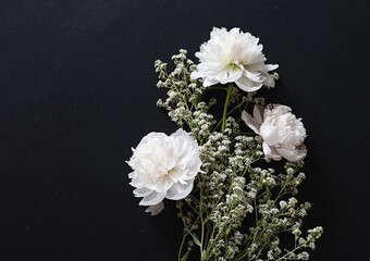 Delicate white flowers and buds arranged beautifully on a dark surface