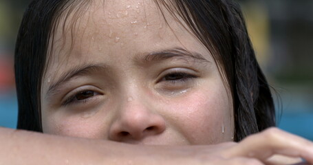 Close-up of a girl's wet face leaning on pool edge in slow motion at 800 fps, with a blurred background, capturing her relaxed expression and highlighting the enjoyment of swimming