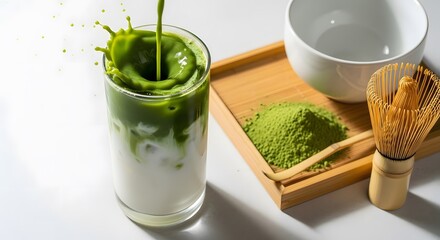 Matcha green tea latte splash with powder and whisk.