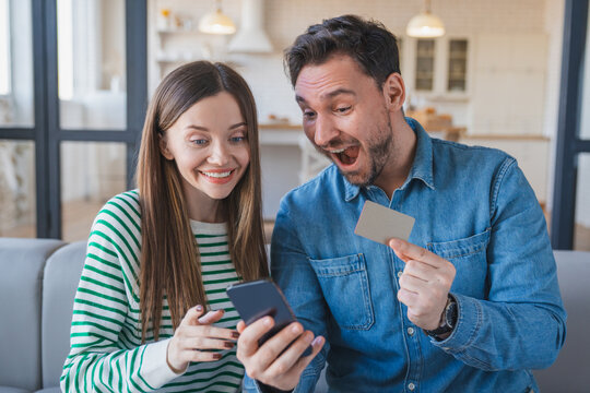 Fototapeta Success, smartphone, happy couple sitting with credit card for online shopping discount and sale. Bonus points ecommerce, Caucasian people on fintech app in home with rewards voucher code and savings