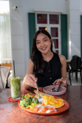 Asian woman smiling enjoying brunch at a cafe