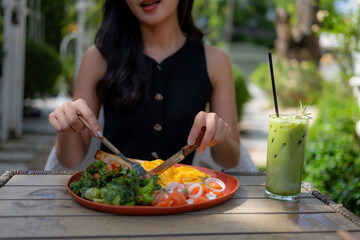 Woman enjoying healthy brunch with iced matcha latte