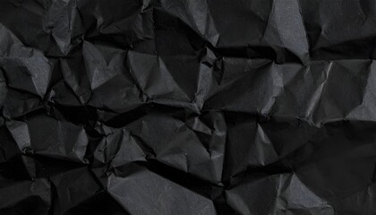 Detailed macro view of a crumpled black paper surface displaying intricate folds and creases for a dramatic background