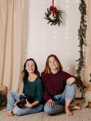 Zwei Frauen, eine mit Kamera, sitzen in einer weihnachtlichen Kulisse