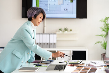 Professional senior interior designers or architects working  in office,  using a laptop and...