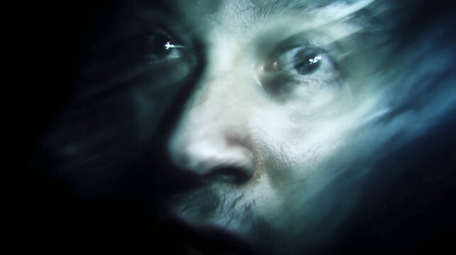 A scary close-up of a face dissolving into a ghost, a terrifying supernatural or paranormal horror concept, a concept of the soul leaving the body.