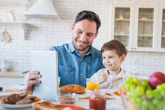 Family, gadget and breakfast kid with father in a home happiness and care. Dad, food, tablet and young child together with parent love and support with healthy drink and youth with a smile