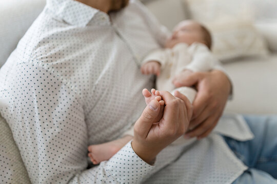 F&uuml;&szlig;e eines winzigen Neugeborenen aus n&auml;chster N&auml;he. Kinderfu&szlig; in den H&auml;nden von Vater, Eltern. Kleine Babybeine. 