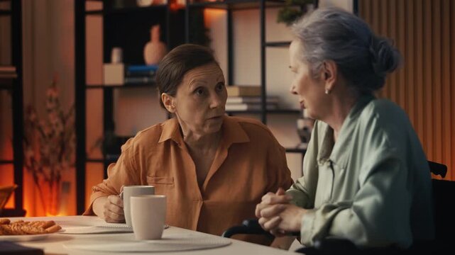 Senior woman wheelchair user discussing news with best friend over tea